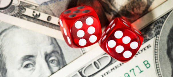 Two red dices on an American one hundred dollar bill.