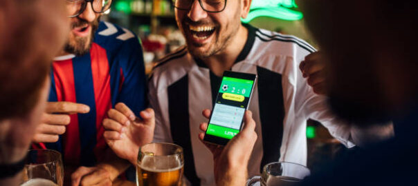 Soccer fans drinking beer at the pub and using mobile app for betting.