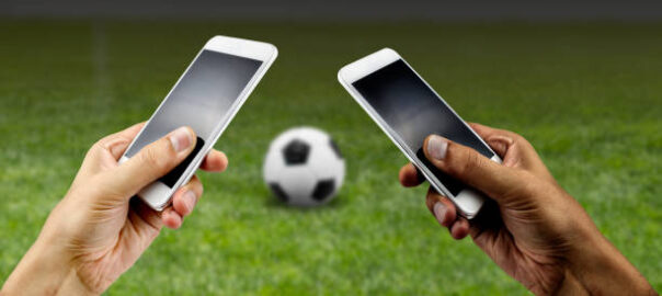 Friends using mobile phone and betting during a football or soccer match